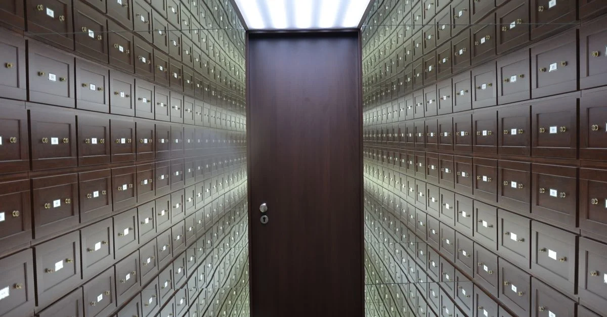 Des coffres en bois bordent les murs d'un coffre-fort moderne et sécurisé avec une porte centrale en bois.