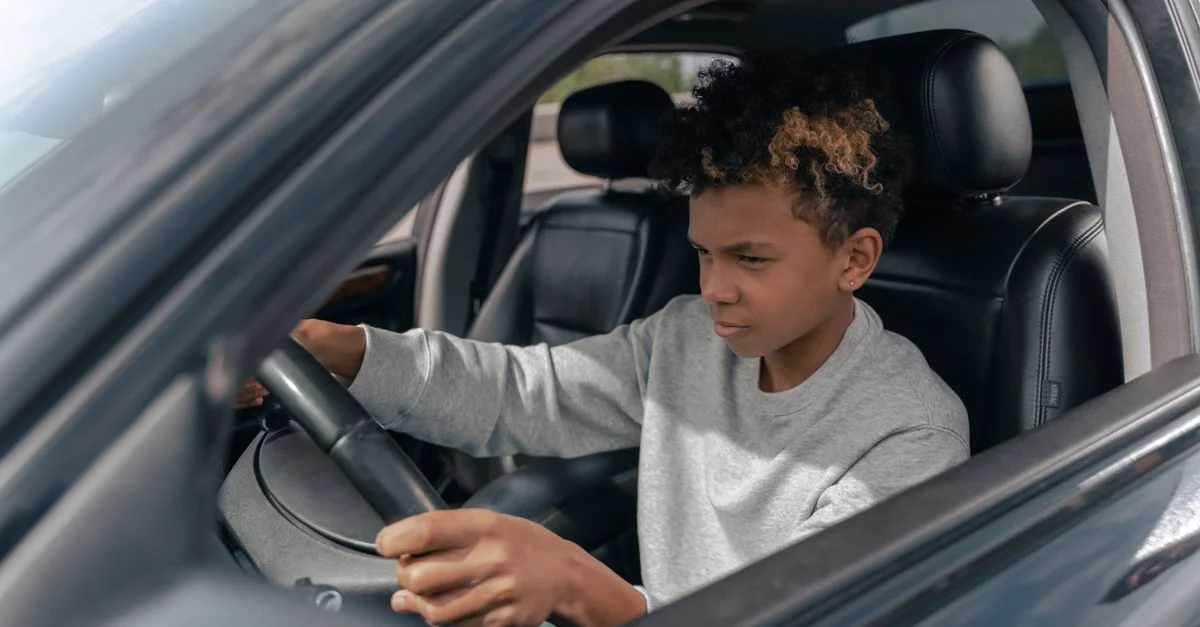 Adolescent apprenant à conduire une voiture avec concentration et détermination.
