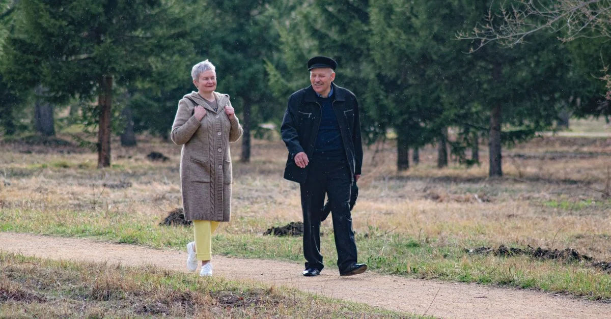 Couple senior heureux se promenant le long d'un chemin dans un parc par un agréable jour de printemps.