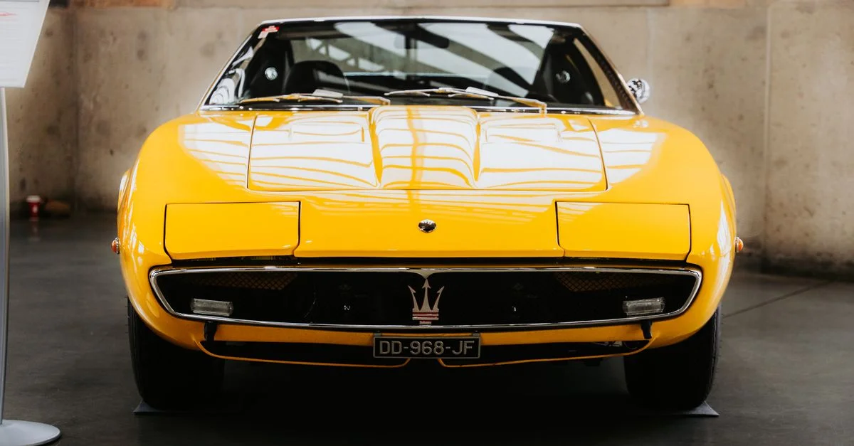 Une voiture de sport jaune classique présentée à l'intérieur, mettant en valeur son design élégant et son attrait vintage.